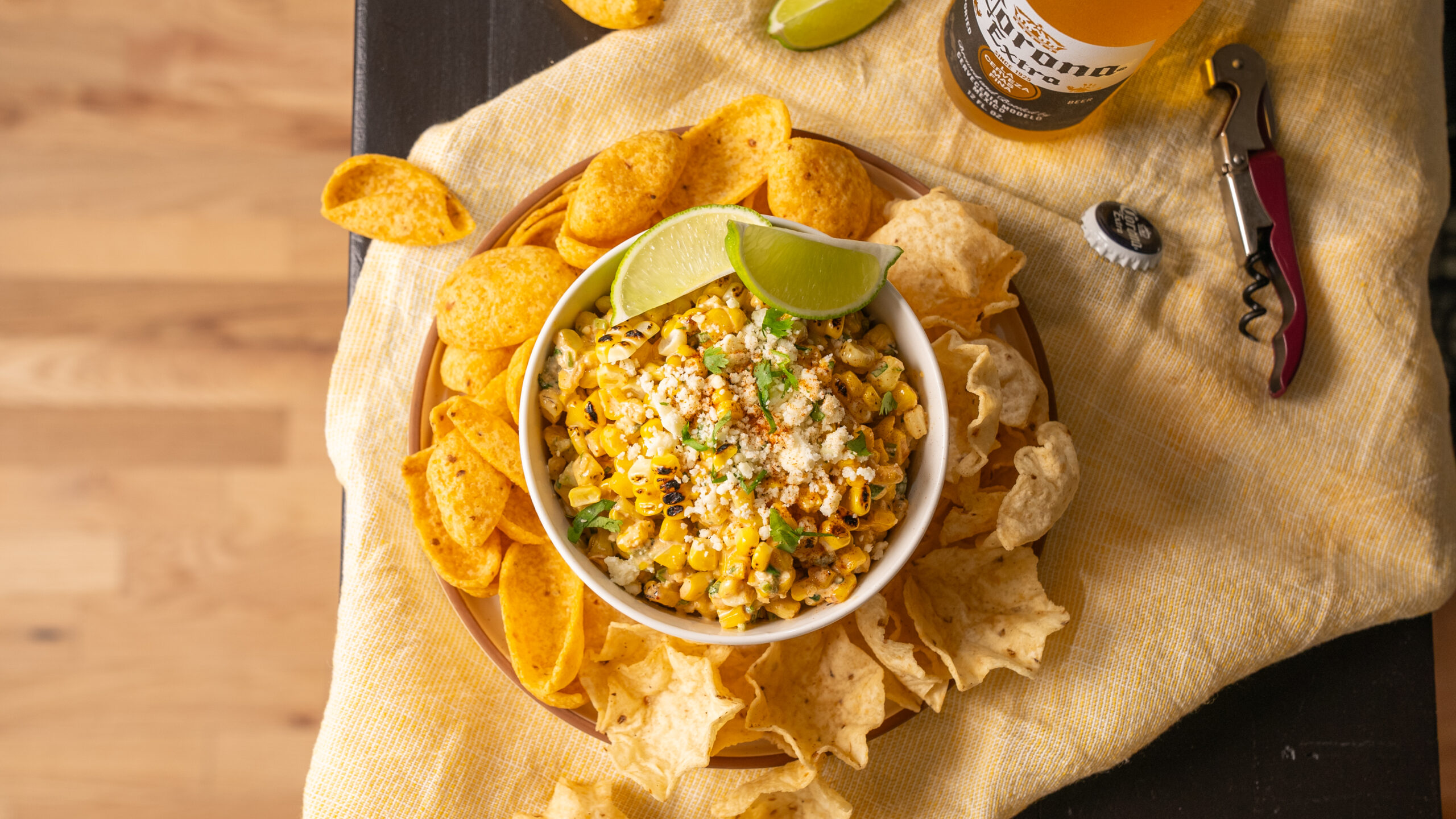Vibrant bar scene featuring corn elote dip, tortilla chips, and a Corona beer. Ideal for showcasing your CPG brand's products through captivating food videography and photography. Enhance your marketing with visually engaging bar setups that attract and engage your audience.