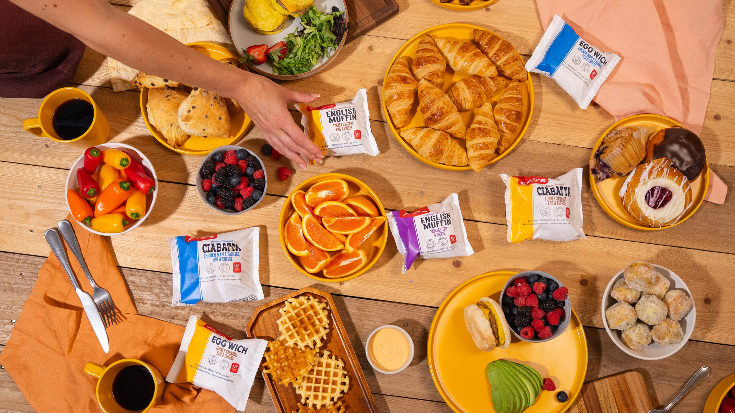 Bright breakfast scene showcasing a delicious CPG food product alongside croissants, bacon, coffee, orange juice, and donuts. Perfect for highlighting your brand's appeal in high-quality food videography and photography. Elevate your marketing with visually stunning breakfast setups that attract and engage your audience.